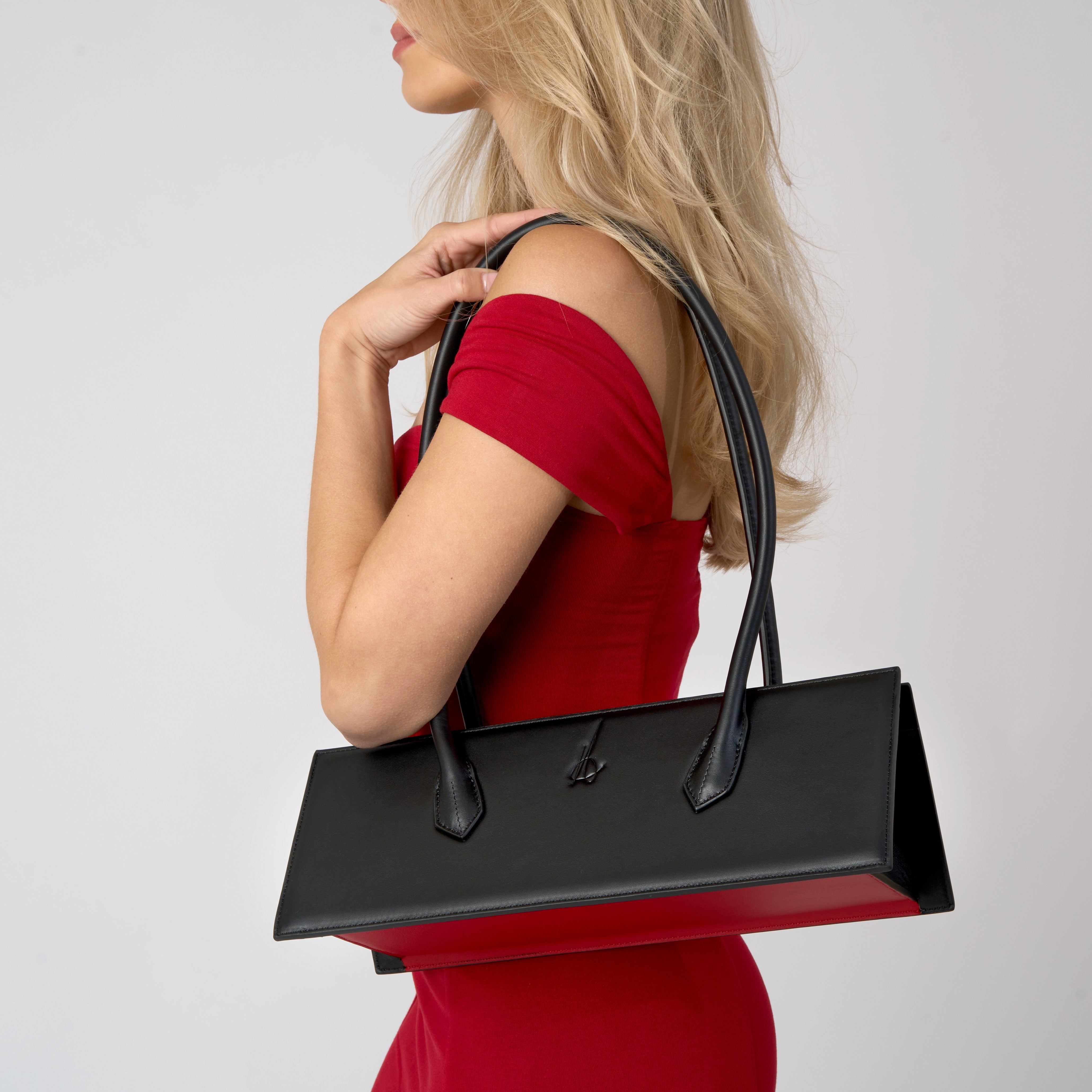 A woman with a black bag with red bottom on her shoulder